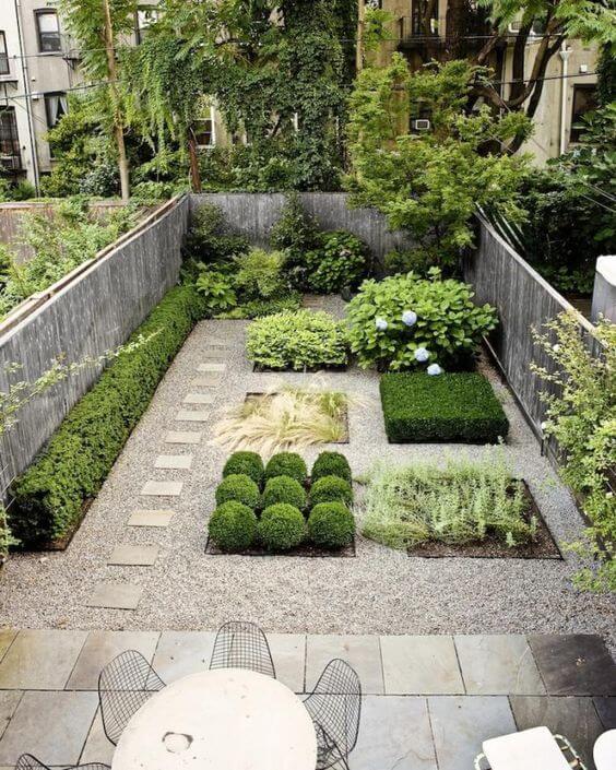 Modern backyard landscaping features low-maintenance plants, a stepping stone pathway, and boxwood spheres in a structured design.