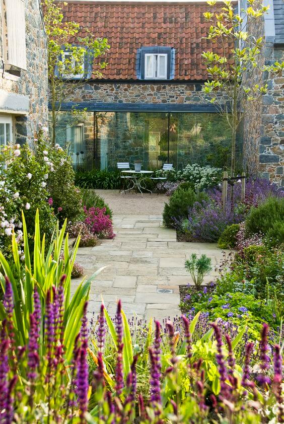 A serene budget-friendly backyard features a stone pathway, vibrant flowers, and a cozy seating area, blending beauty with practicality.