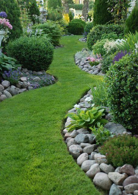 Garden pathway with serpentine layout, lush grass, natural stone borders, and flowering plants, enhancing floral aesthetics and inviting ambiance.