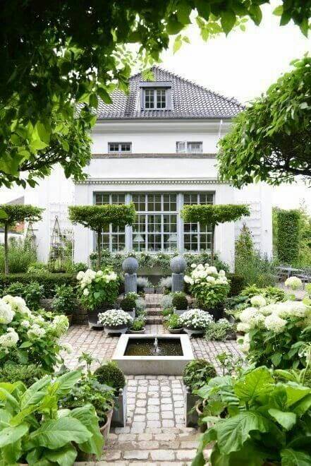 Symmetrical flower landscape design featuring a rectangular water feature, cobblestone pathways, lush hydrangeas, and topiary trees.