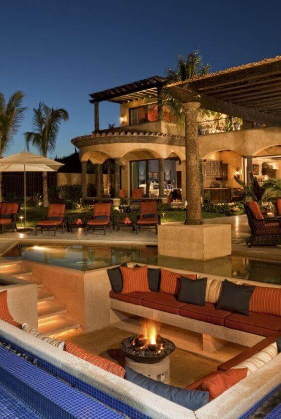 Luxurious backyard with a stone fire pit and sunken seating area, surrounded by palm trees, creating a cozy, tropical atmosphere.