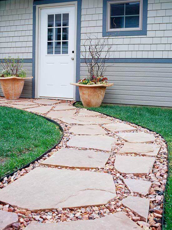 Winding flagstone and gravel walkway, 3 feet wide, leads to a grid-patterned white door, flanked by terracotta planters and green grass.