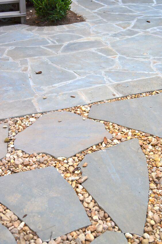 Flagstone and gravel walkway featuring irregularly shaped flagstones and small pebbles, designed for drainage and aesthetic appeal.