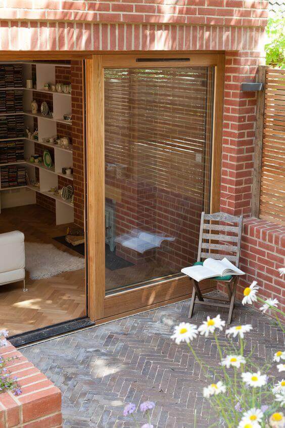 Outdoor living space featuring a brick-laid terrace and large sliding glass door framed in wood, enhancing light and accessibility.