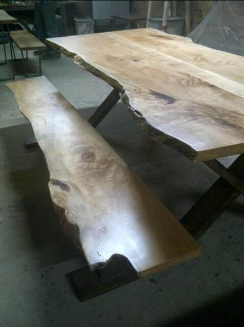 Wooden live edge dining table made from natural timber slabs, measuring 2.5m by 1m, with a sturdy metal frame and unique grain patterns.