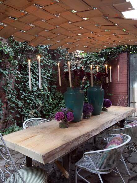 Rustic live edge dining table made from a single slab, surrounded by white metal-framed chairs, adorned with teal vases and purple hydrangeas.