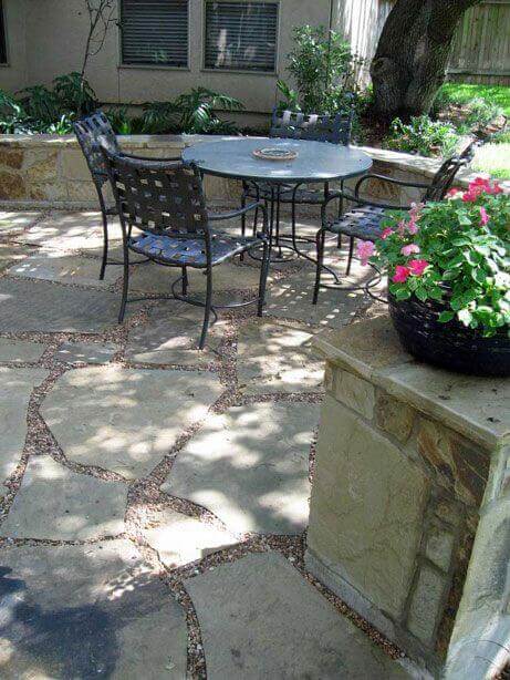 Flagstone and gravel walkway features irregularly shaped stones set in a natural pattern, connecting outdoor dining and lush gardens.