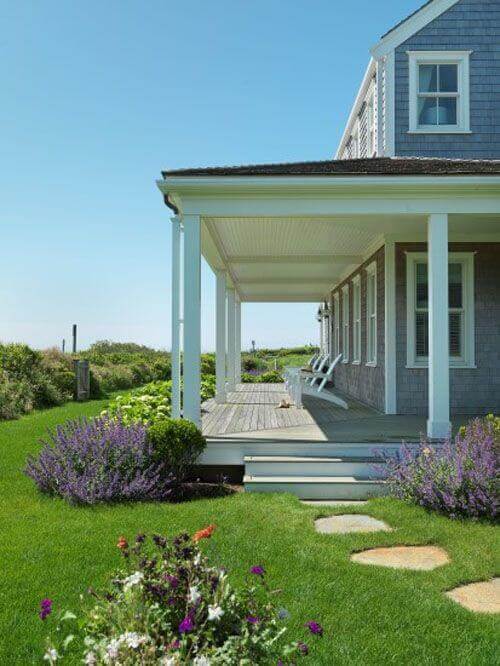 Spacious back porch with wooden decking, leading to a lush lawn and clusters of lavender, ideal for relaxation and outdoor living.