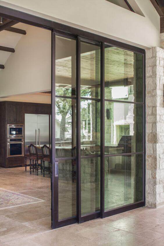 Sliding glass doors with a dark metal frame, 8 feet tall and 6 feet wide, enhancing indoor-outdoor flow and natural light. Ideal for warm climates.