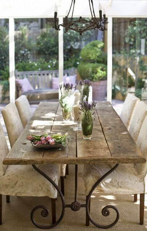 Rustic live edge dining table made from reclaimed timber, surrounded by six comfy upholstered chairs, with a floral centerpiece and ambient lighting.