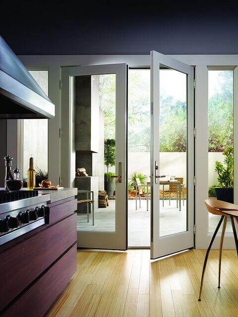 Bifold glass doors transition seamlessly from a modern kitchen to an outdoor patio, framed in sleek aluminum, enhancing natural light.