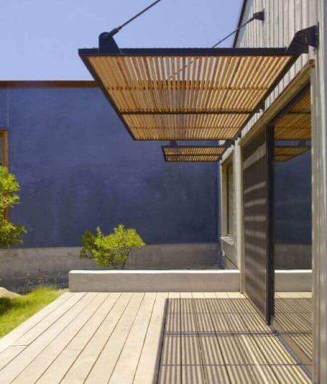 Modern wood deck featuring natural slats and a concrete base, extending 2 meters for shaded outdoor space, contrasting with a blue wall.