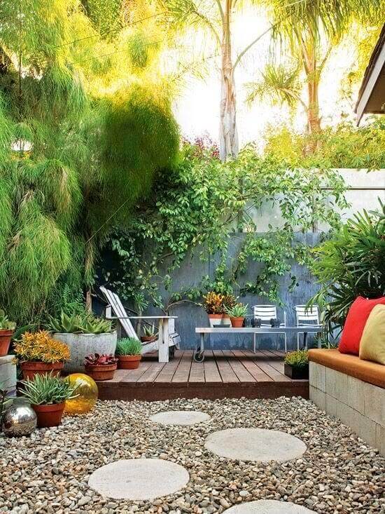 Compact wooden deck with dark-stained planks, surrounded by gravel pathways and potted succulents, offering a contemporary outdoor seating area.
