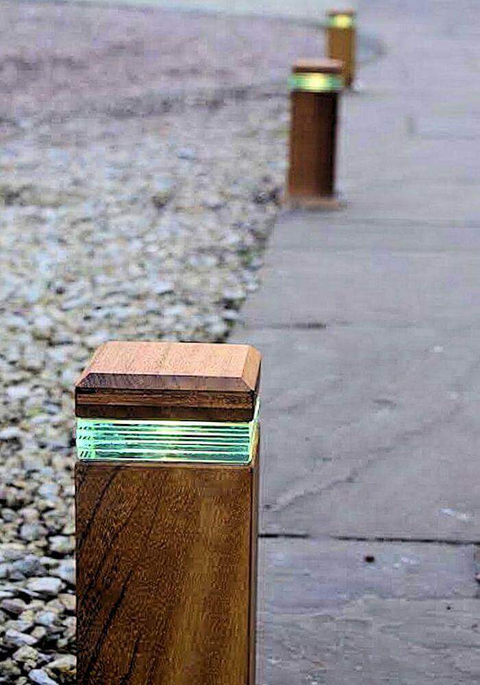 Wooden posts with integrated LED lights line a pedestrian pathway, enhancing safety and aesthetics. Posts are 1 meter tall, spaced 1.5 meters apart.