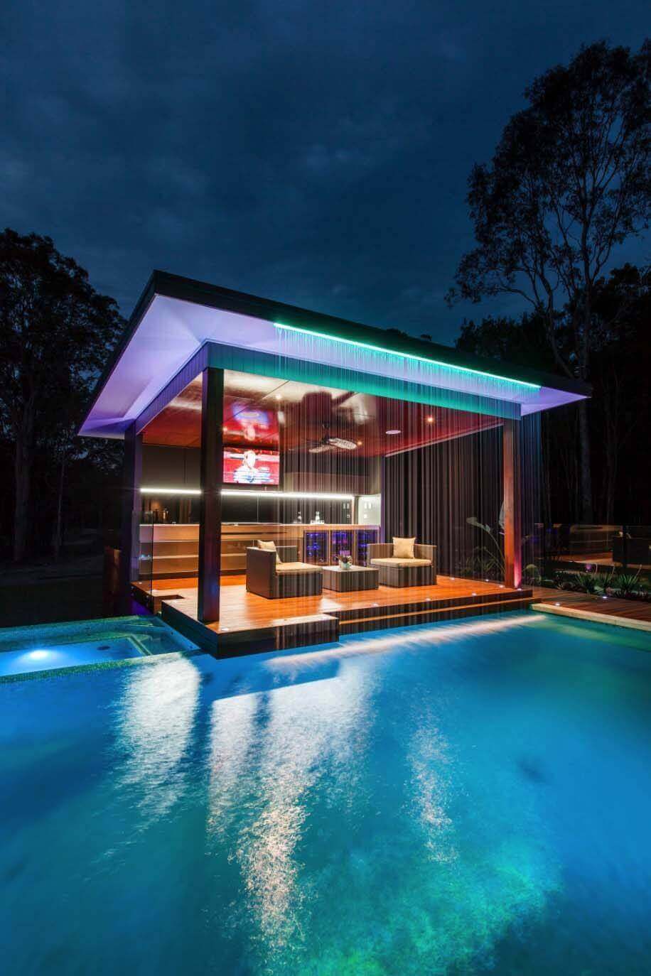 Luxurious pool area with modern outdoor furniture, including a sleek pavilion, lounge space, and a dark-stained timber deck.