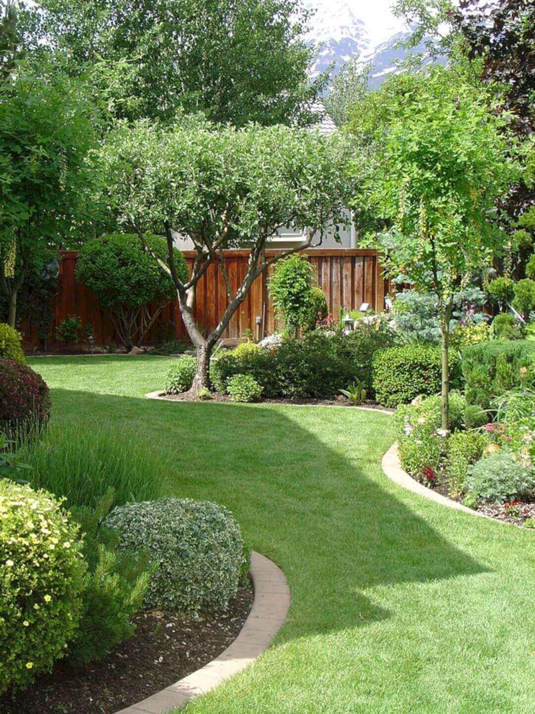 Meticulously designed garden featuring lush lawns and brick edging pathways, surrounded by varied trees and shrubs for visual interest.
