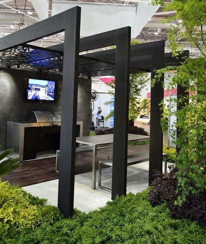 Modern outdoor furniture features a sleek steel framework, polished metal table, and a stainless steel grill, surrounded by low-maintenance plants.