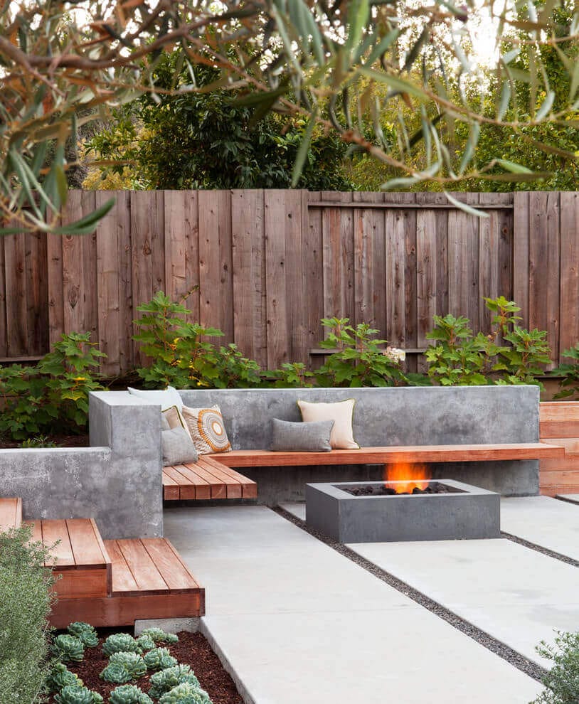 Modern outdoor space featuring a rectangular fire pit, concrete seating with wood accents, and low-maintenance succulents for a cozy gathering area.