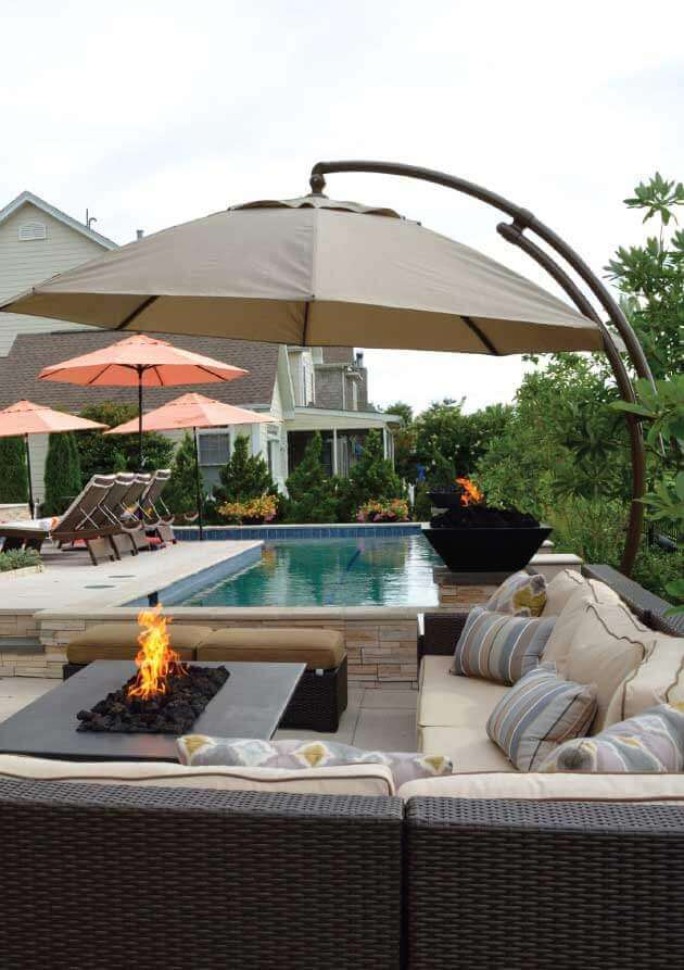 Contemporary patio with a rectangular pool (16x8 ft), stone deck, oversized umbrellas, and sectional sofas for relaxation.