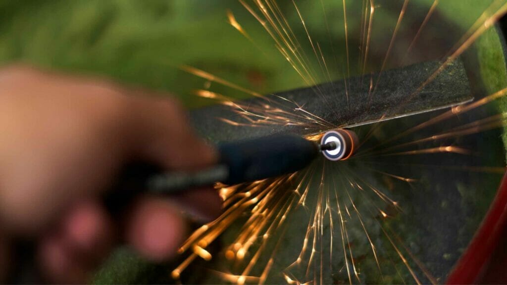 Photo of lawn mower blades being sharpened with a sharpening stone.