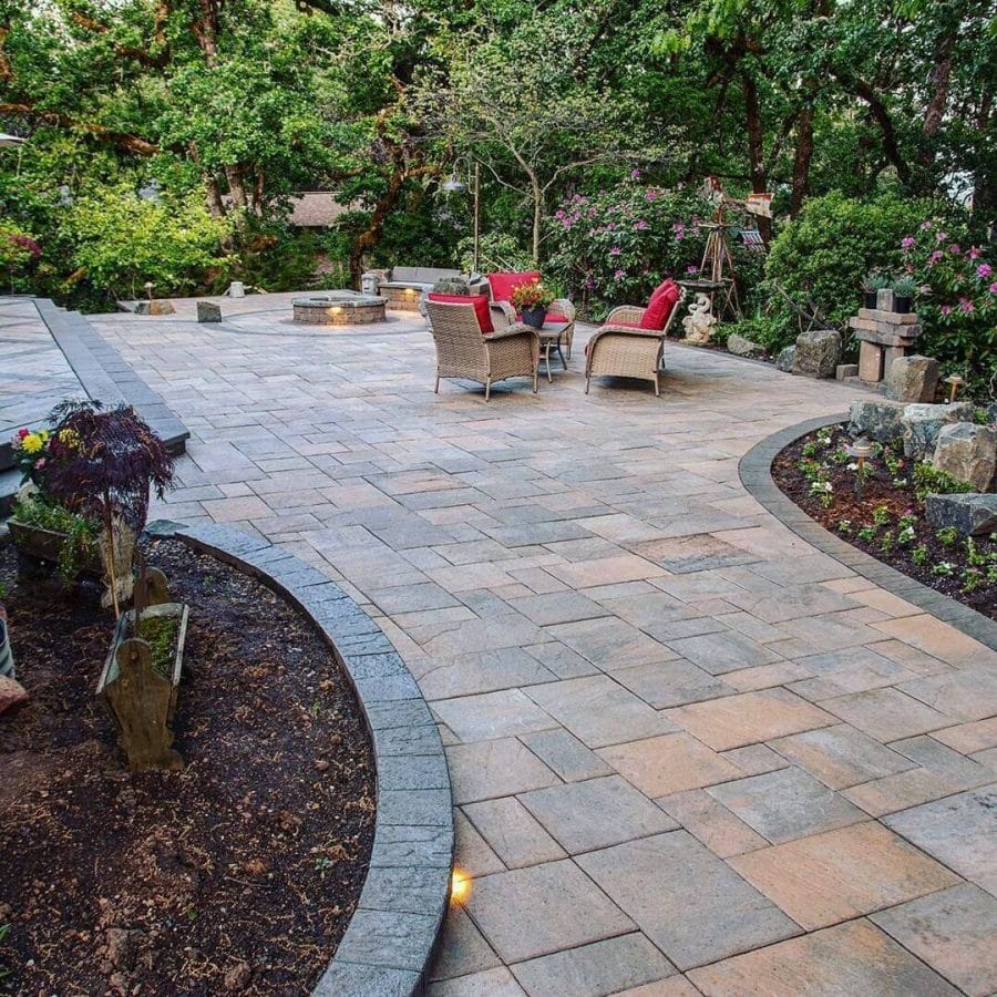 Spacious patio with natural stone pavers, fire pit, and native plants. Ideal for budget-friendly backyard landscaping ideas.