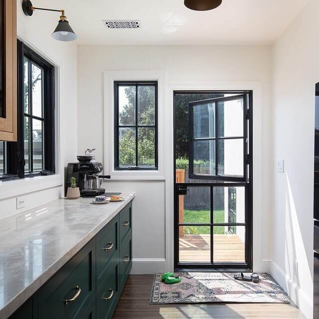 Modern kitchen featuring dark green cabinetry and a black-framed glass patio door, enhancing natural light and outdoor access.