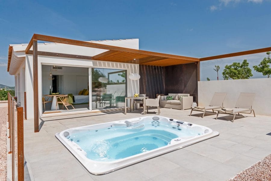 Swim Spa features a modern hot tub on a textured tile patio, surrounded by a minimalist pergola and contemporary seating, ensuring relaxation.